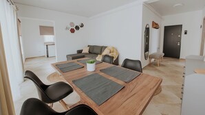 A modern dining area with a wooden table, black chairs, and a grey rug. - THE NOOK APARTHOTEL  (Timisoara)