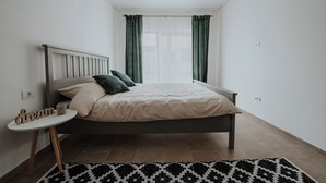 A bedroom with a bed, a bedside table, a small round table with a candle, and a patterned rug. - THE NOOK APARTHOTEL  (Timisoara)