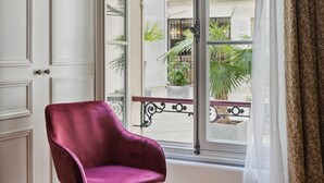 A room with a large window, a red patterned rug, and a purple chair. - Etoile Apartment (G1) – Luxury Two-Bedroom (Paris)