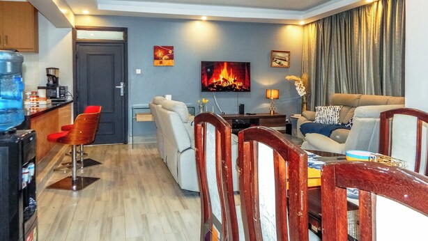 A modern living room with a sofa, chairs, a TV, and a coffee machine. - 4 minutes to Two Rivers Mall! Family-sized condo with a fully functional Kitchen (Ruaka)