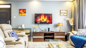 A living room with a TV, sofa, coffee table, and a fireplace. - 4 minutes to Two Rivers Mall! Family-sized condo with a fully functional Kitchen (Ruaka)