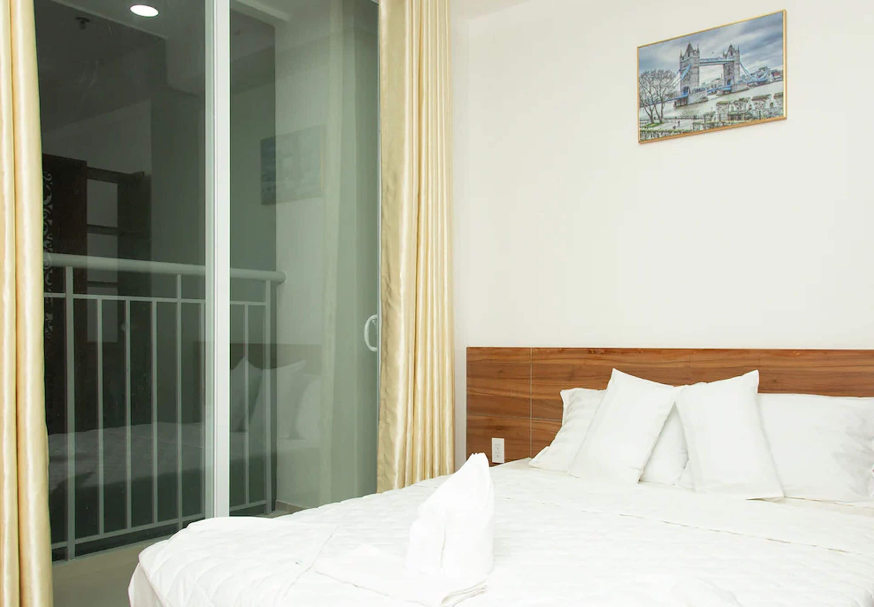 Una habitación de hotel con una cama, un cuadro de un puente y una puerta corredera de vidrio.