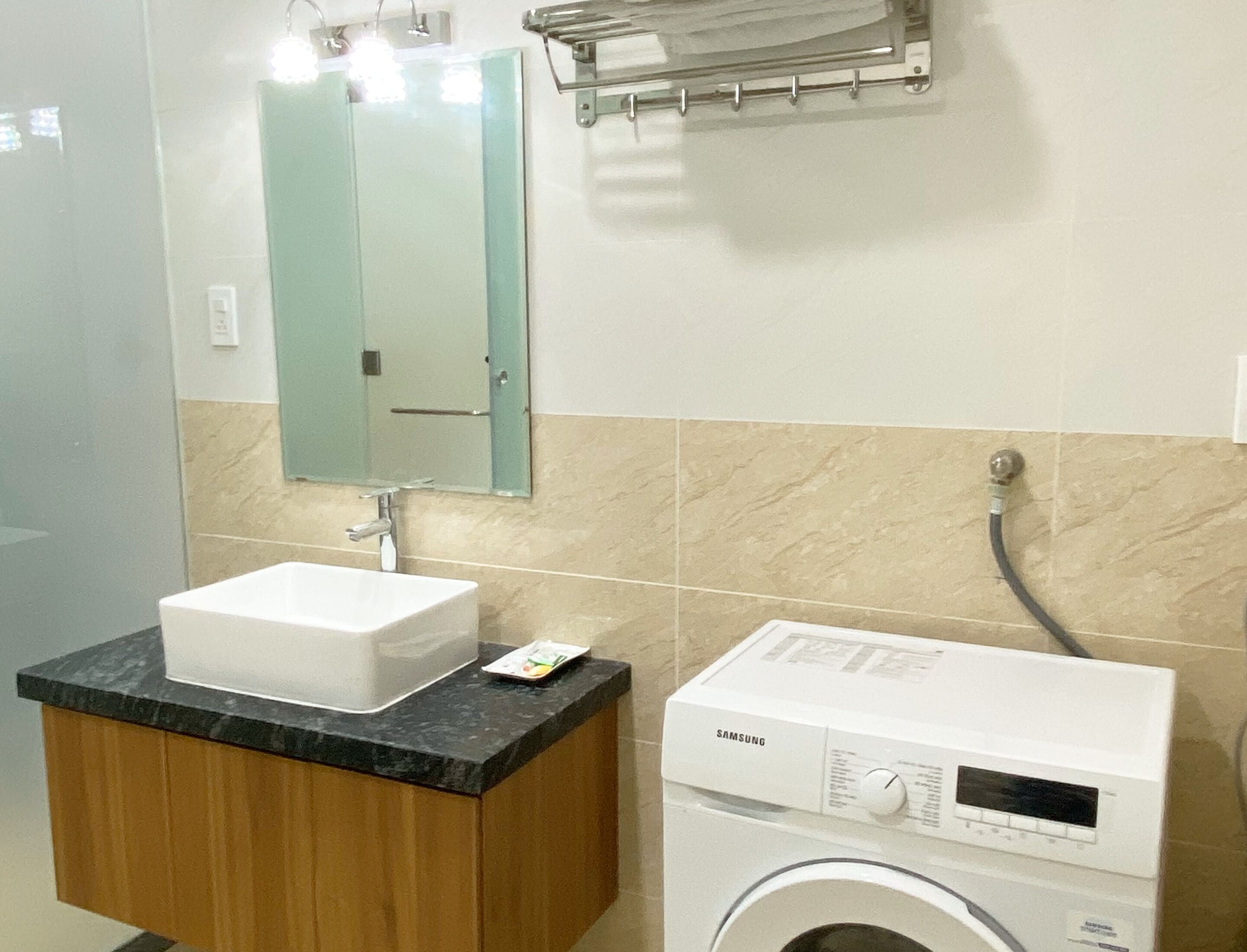 A bathroom with a sink, mirror, towel rack, and a washing machine.