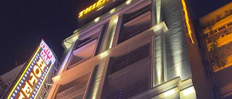 A hotel with a prominent neon sign reading "THIEN TAI HOTEL" and a balcony with railings.
