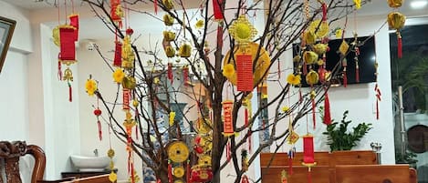 Un árbol chino tradicional decorado con adornos rojos y dorados, ubicado en una maceta de cerámica.