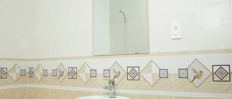 Un baño con lavamanos blanco, un espejo y una ducha.