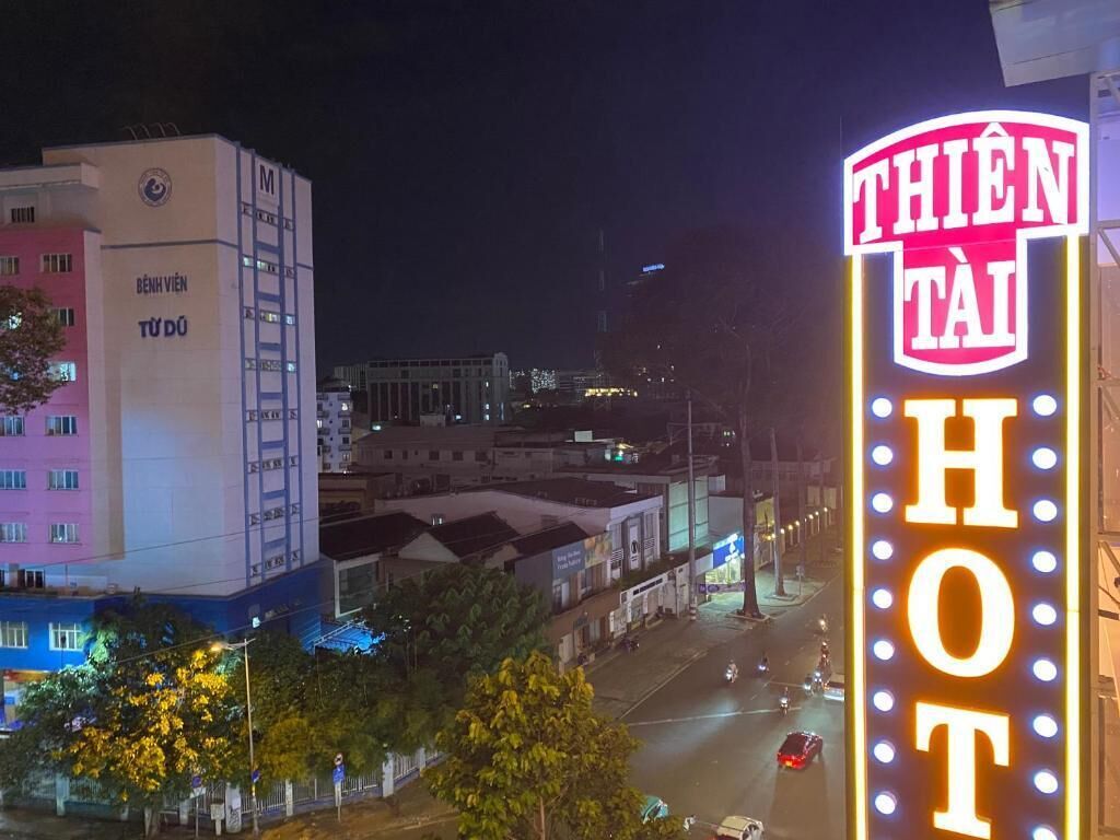 A building with a prominent neon sign reading "THIEN TAI HOT" and a sign on the building that says "BENH VIEN TUDO".