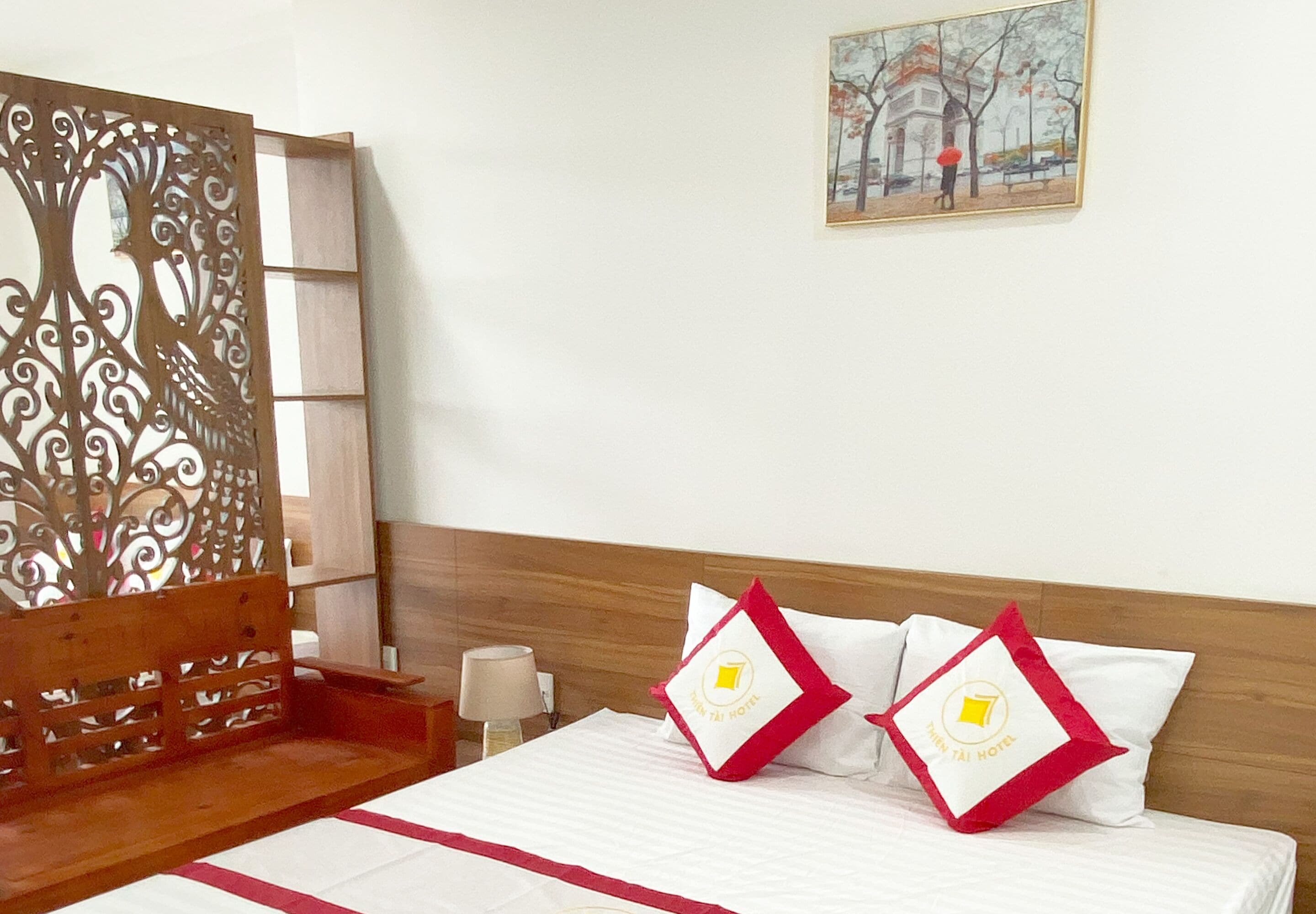 Habitación de hotel con cama, un panel de madera decorativo, una mesita de noche y un cuadro en la pared.