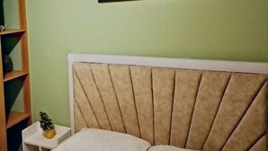 Een slaapkamer met een bed, een nachtkastje, een kleine plant en een aan de muur hangend schilderij.