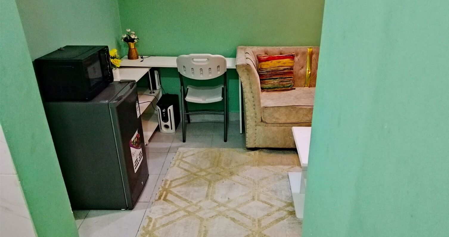 Una cocina compacta con refrigerador, microondas y una pequeña mesa de comedor con una silla.