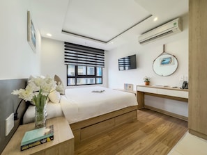 Quarto moderno com cama, mesa de cabeceira e área de estudo.