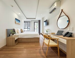 A modern hotel room with a bed, bedside table, desk, chair, laptop, phone, TV, and a large mirror. - CityHouse NEST LightHouse Saigon (Ho Chi Minh City)
