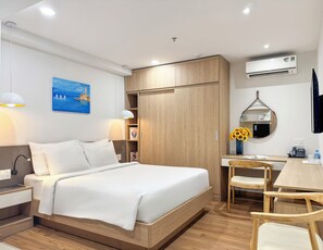 A modern hotel room with a bed, bedside table, lamp, desk, chair, and an air conditioning unit. - CityHouse NEST LightHouse Saigon (Ho Chi Minh City)