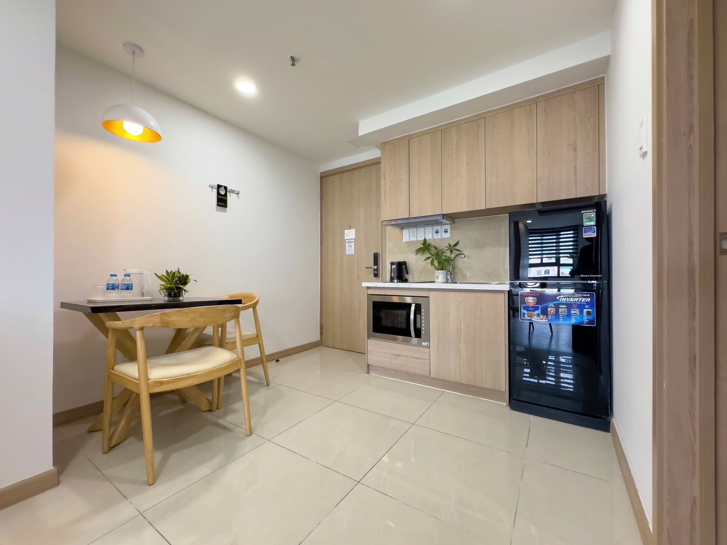 A modern kitchen with wooden cabinets, a black refrigerator, a microwave, and a dining area with a table and chairs.
