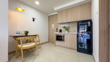 A modern kitchen with wooden cabinets, a black refrigerator, a microwave, and a dining area with a table and chairs.
