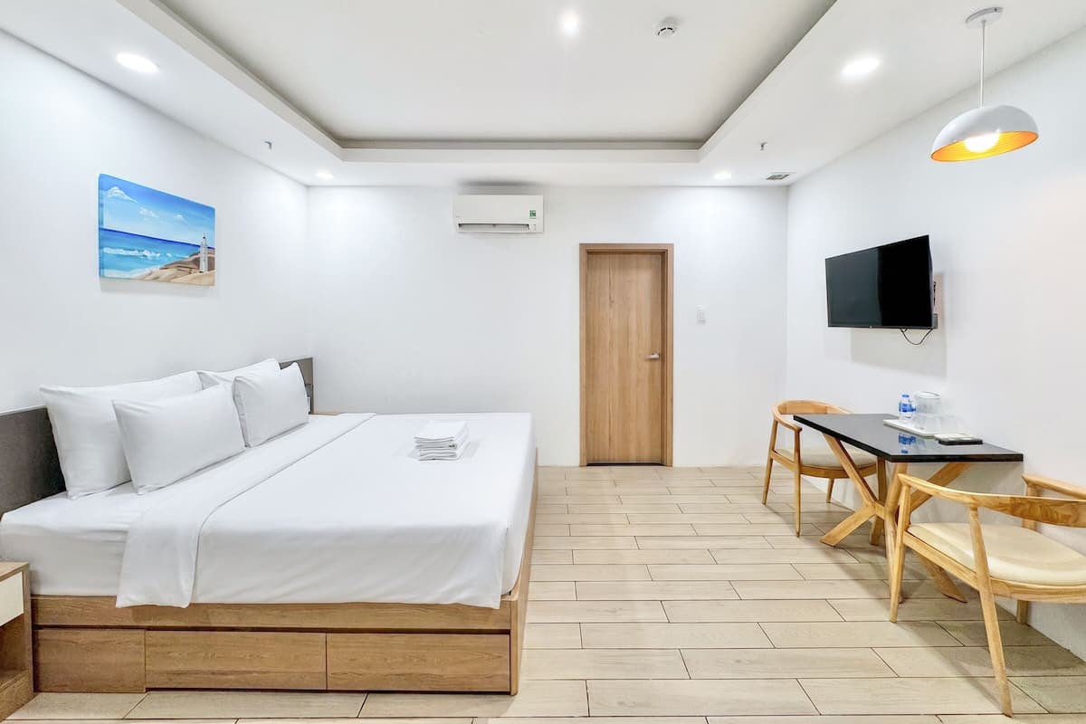 Ein Hotelzimmer mit Bett, Schreibtisch, Stuhl, Fernseher und einem Gemälde an der Wand.
