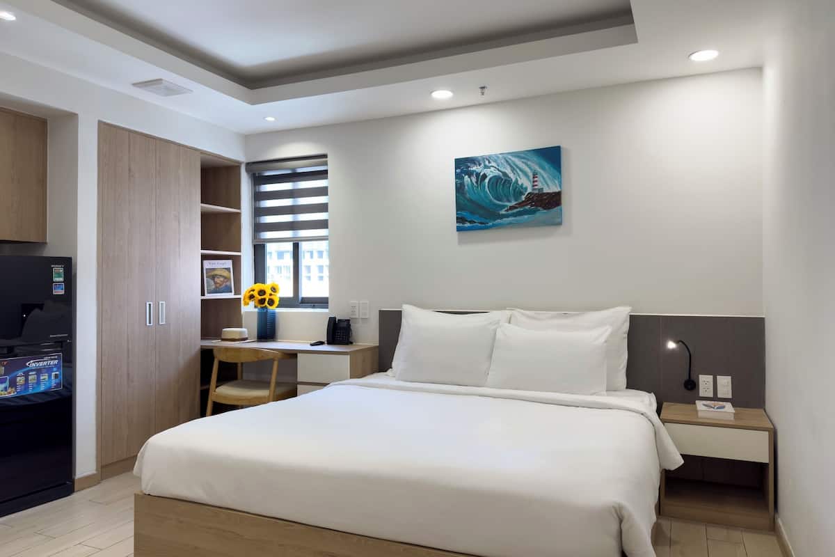 Ein Schlafzimmer mit Bett, Schreibtisch, Stuhl, Fernseher und einem Bild an der Wand.