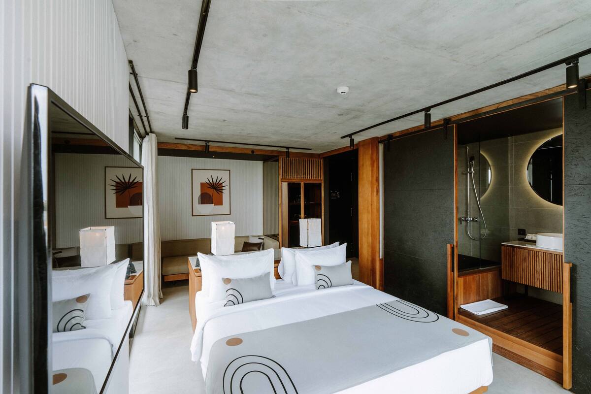 Una habitación de hotel moderna con una cama grande, un baño independiente y vistas a la ciudad.