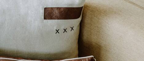 A pillow with a brown leather patch and the letters "XXX" on a beige fabric.