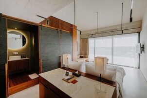 Ett modernt hotellrum med ett badrum i marmor, trädetaljer, ett stort fönster och en minimalistisk design.