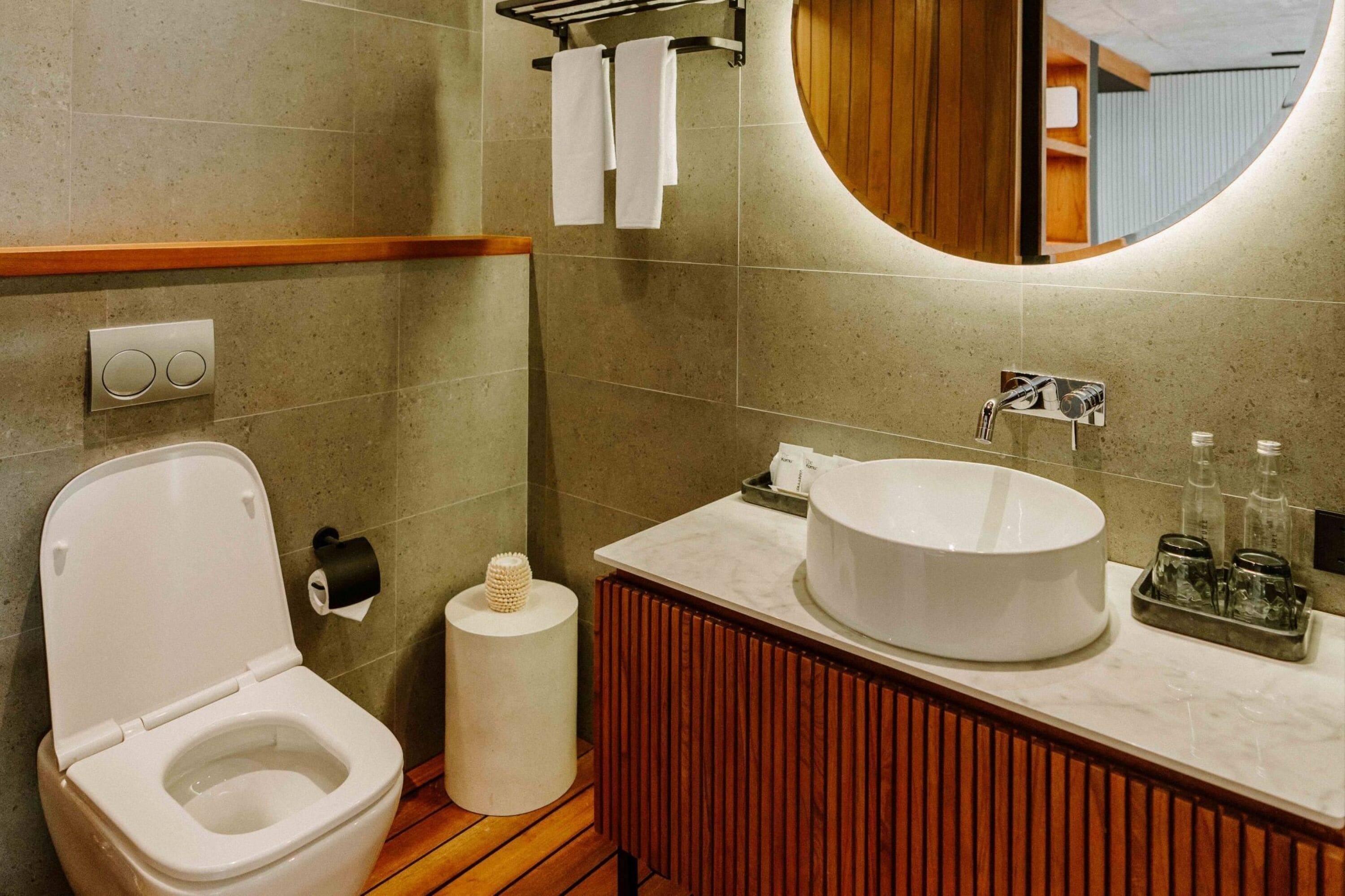 Une salle de bain moderne avec des toilettes, un lavabo et un miroir.