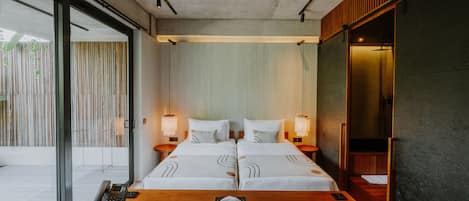 A modern hotel room with a large bed, bedside tables, a desk with a phone, and a view of the outside.