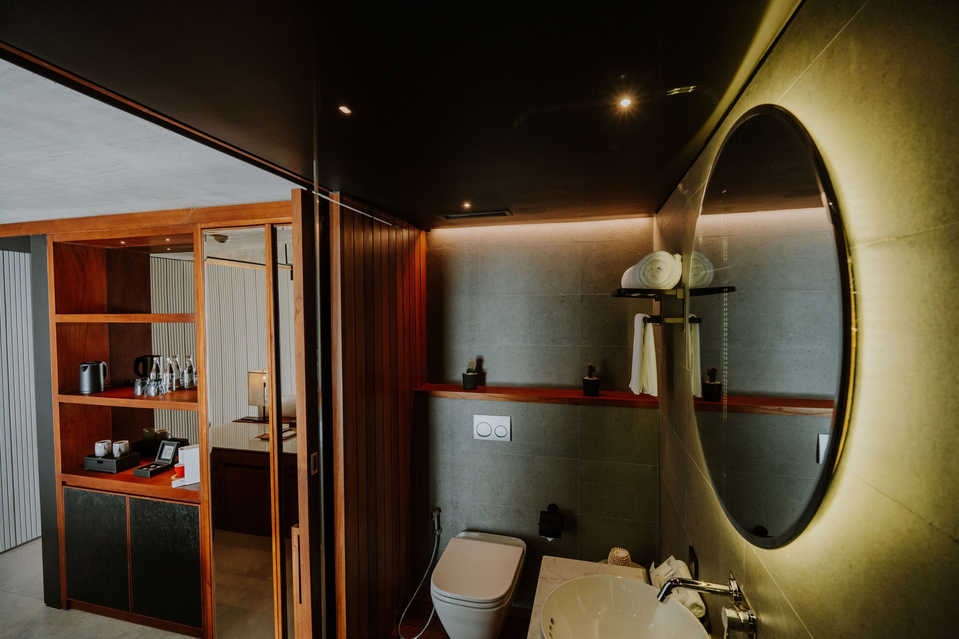 A modern bathroom with a large mirror, a toilet, a sink, and a shower area.