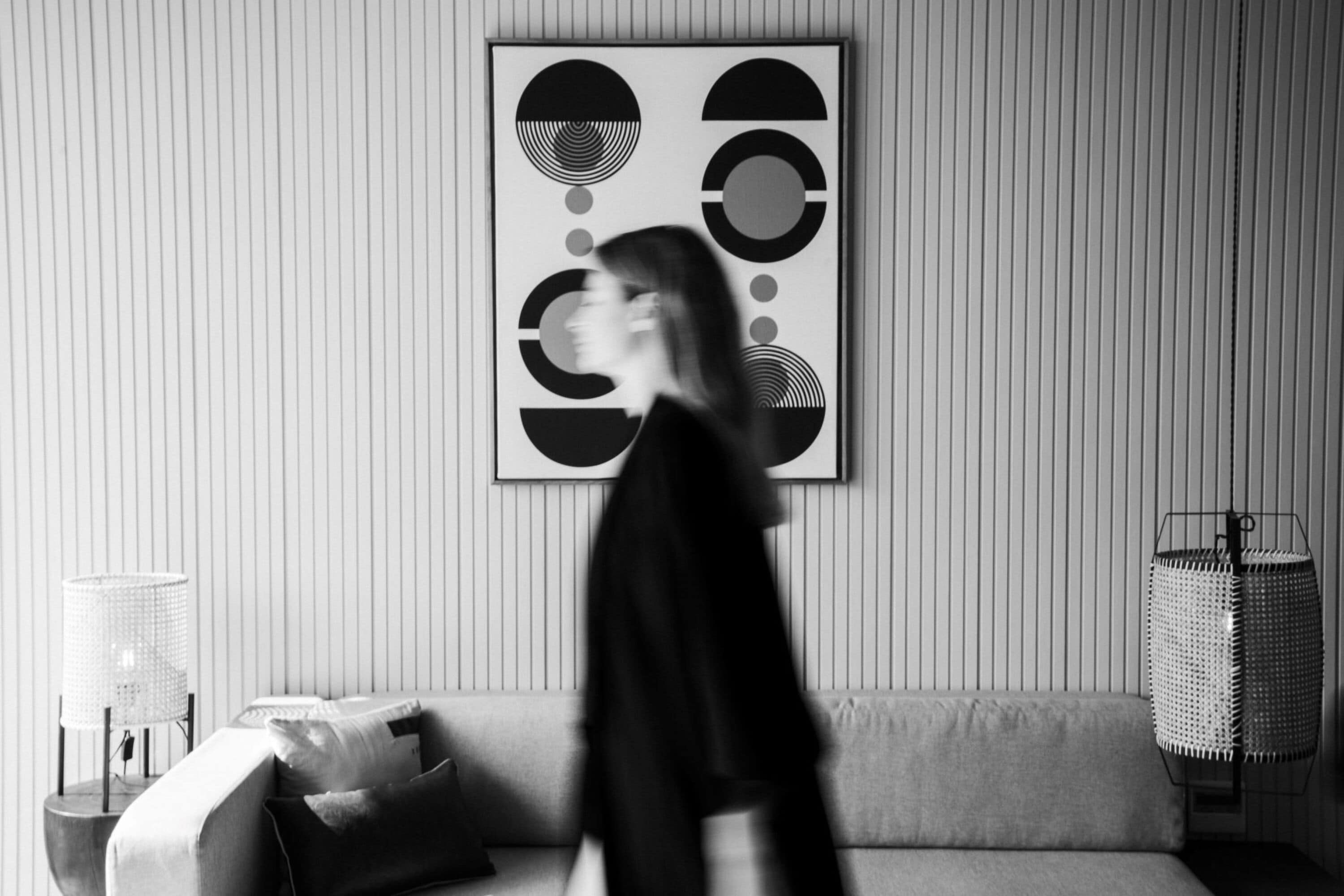 A modern living room with a sofa, a lamp, and a geometric art piece on the wall.
