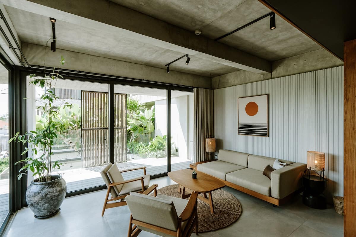 Una sala de estar moderna con un sofá, sillas, una mesa de centro y un ventanal con vistas a zonas verdes.