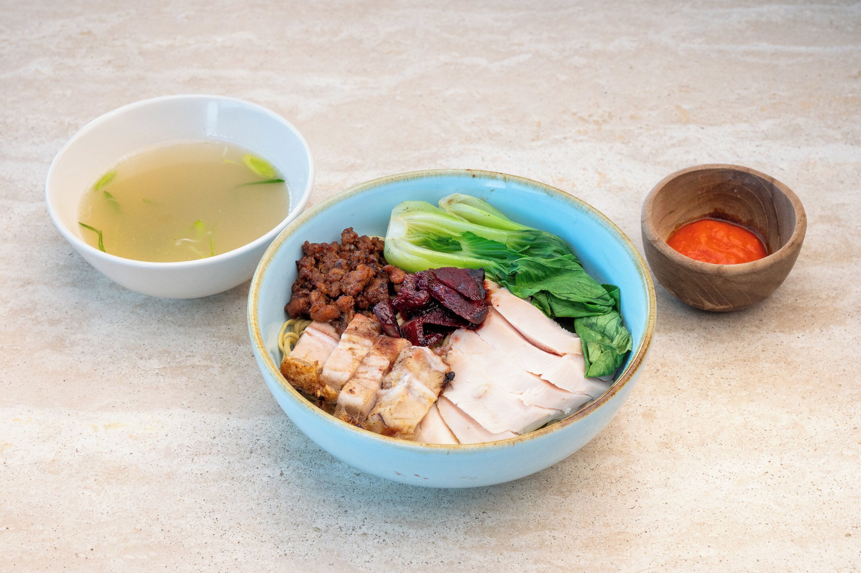 A bowl of food with various ingredients including meat, vegetables, and a side of soup.