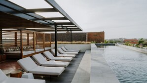 Un área de piscina en la azotea con tumbonas y una pérgola.