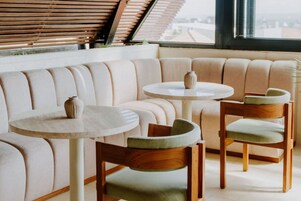 A modern interior with a curved sofa, two round tables, and wooden chairs.