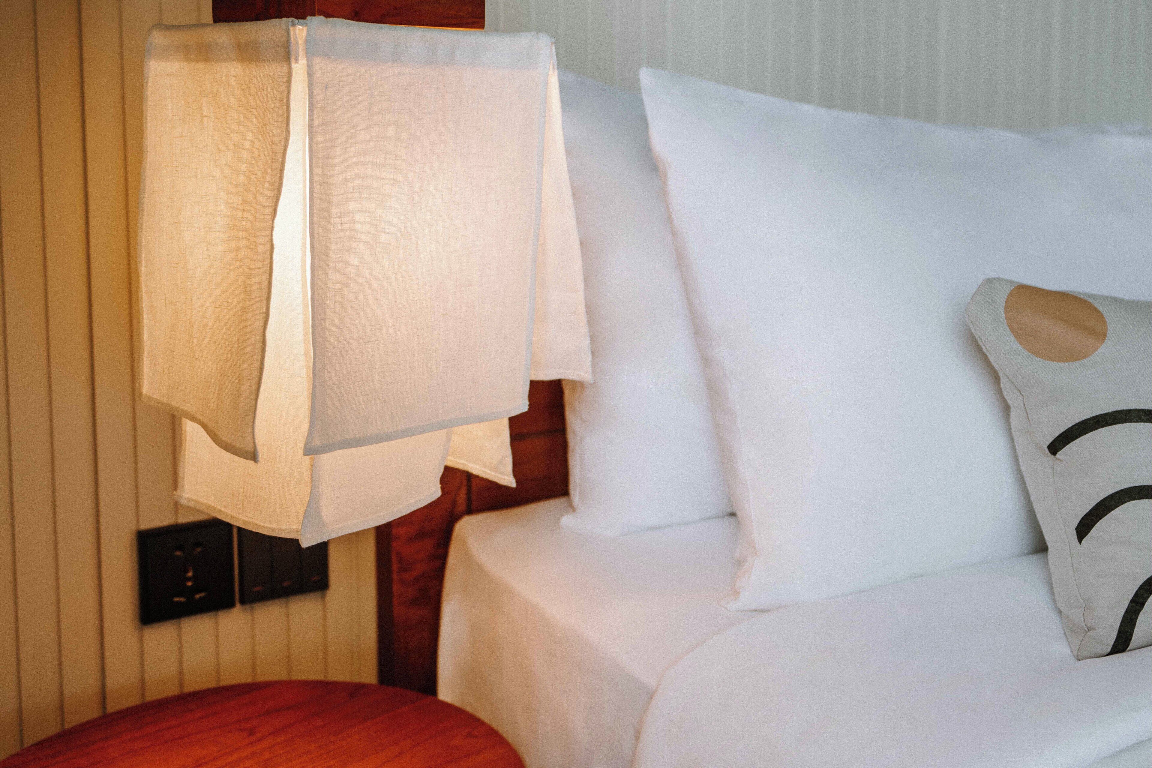 A neatly made bed with white linens and a single decorative pillow.