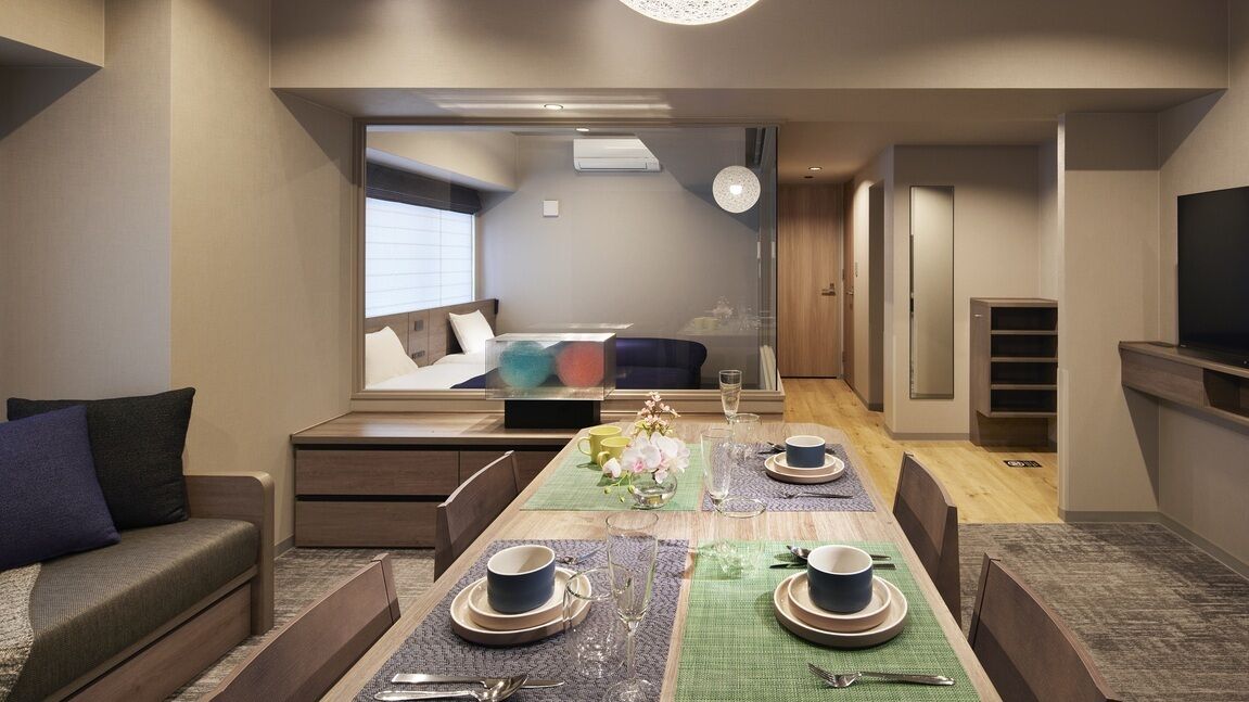 A modern living room with a dining area, a sofa, a TV, and a small kitchen area.