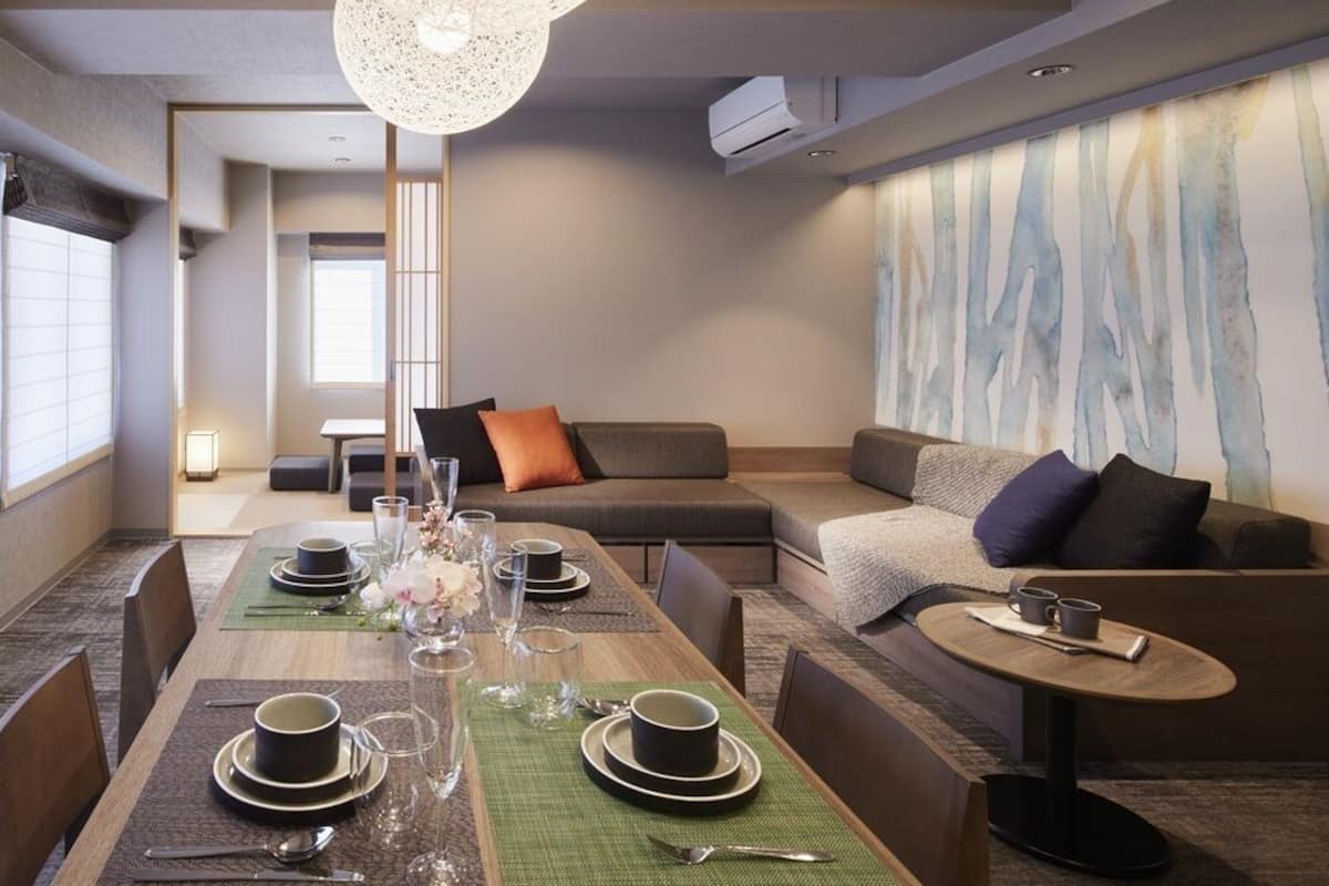 A modern hotel room with a dining area, a sofa, and a small table.