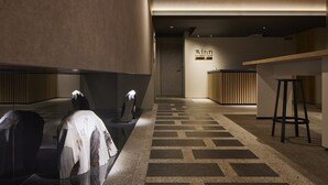 Un hall de hotel con mostrador de recepción, una zona de estar y un suelo estampado.
