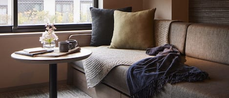 Un coin salon confortable avec une table ronde, un vase de fleurs et une vue par la fenêtre.