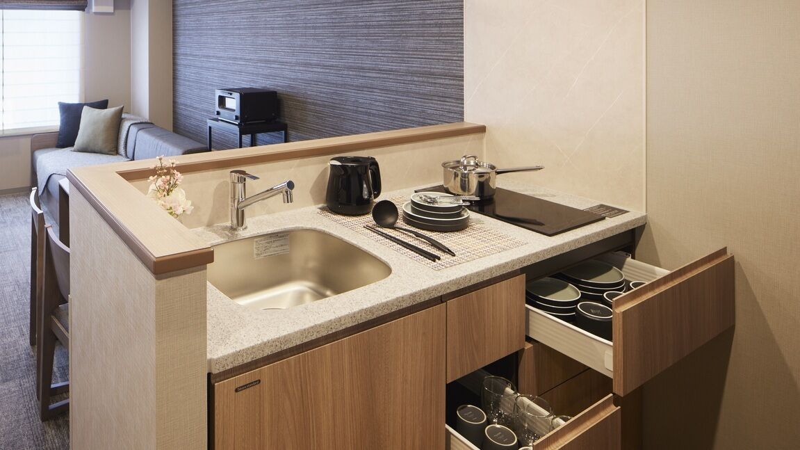 A compact kitchenette with a sink, coffee maker, and storage drawers.