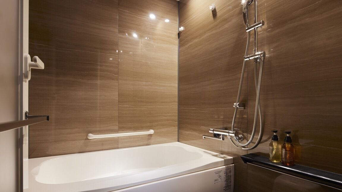 A modern bathroom with a white bathtub, a glass-enclosed shower, and a vanity with toiletries.