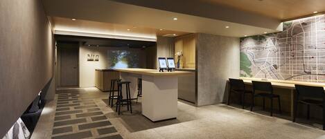 A modern hotel lobby with a reception desk, bar area, and seating.