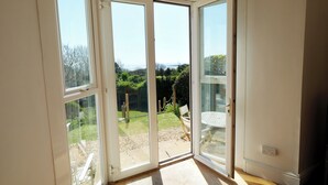 A room with a sliding glass door leading to a patio with outdoor furniture and a view of the sea. - The Retreat - 5 Bedroom House - Horton (Swansea)
