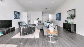 A modern living room with a sofa, a coffee table, a TV, and a fireplace. - Princess Wharf w/ Balcony

 (Auckland)
