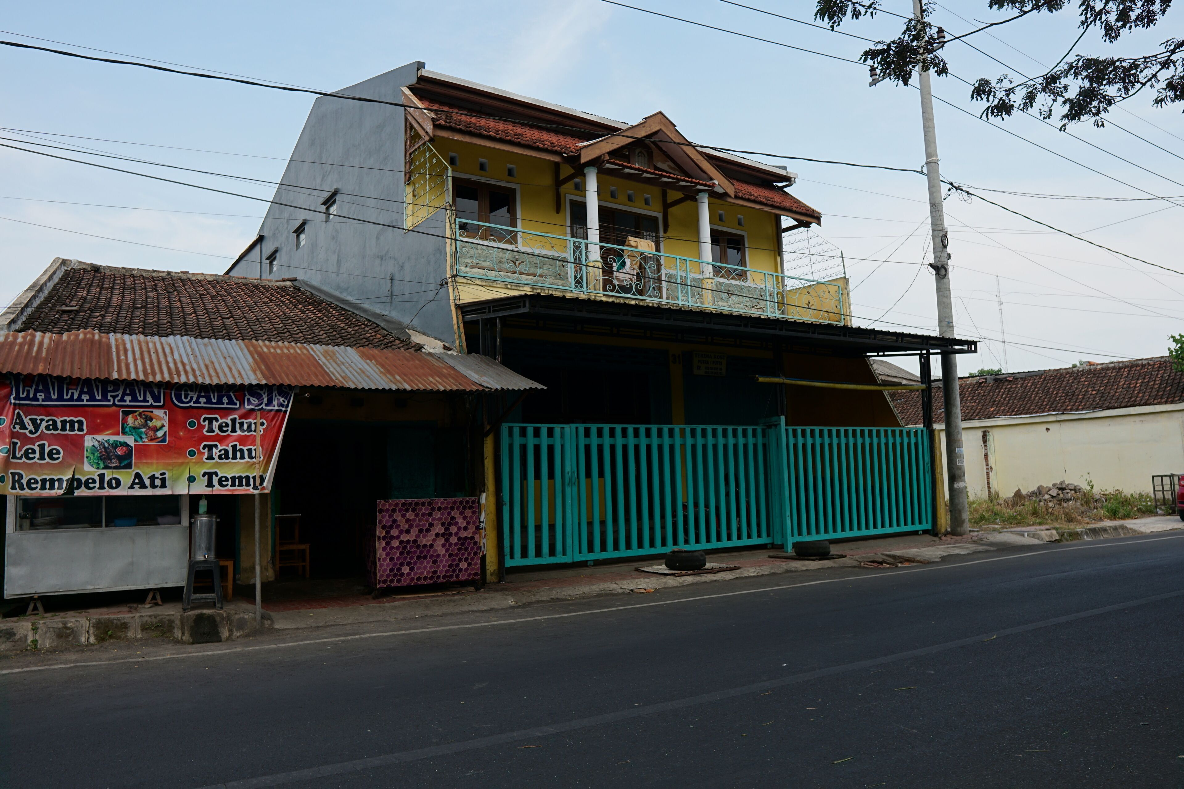 A two-story building with a balcony and a signboard advertising food items.