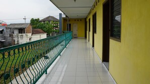 A corridor with a green railing, yellow walls, and a tiled floor. - Hotel O Yoko Kost Syariah (Bondowoso)