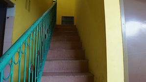 A staircase with a green railing leading up to a landing. - Hotel O Yoko Kost Syariah (Bondowoso)