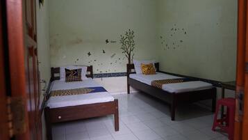 A room with two wooden beds, white bedding, and a red stool.