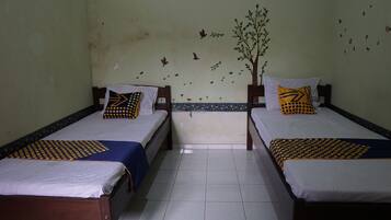 Une chambre avec deux lits simples, chacun recouvert d’une couvre-lit à motifs et agrémenté d’oreillers assortis. Les murs sont décorés de motifs floraux et d’arbres, et le sol est carrelé.