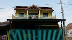 A two-story building with a balcony and a gated entrance. - Hotel O Yoko Kost Syariah (Bondowoso)