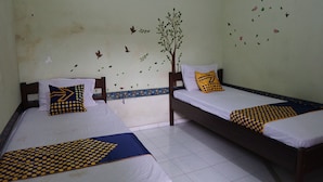 A room with two beds, each with a white sheet and a blue and yellow polka dot blanket. There are decorative wall stickers, including a tree and birds. - Hotel O Yoko Kost Syariah (Bondowoso)