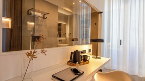 A modern bathroom with a large mirror, a sink, and a shower area. - Mamalu Studios and Suites (Naples)